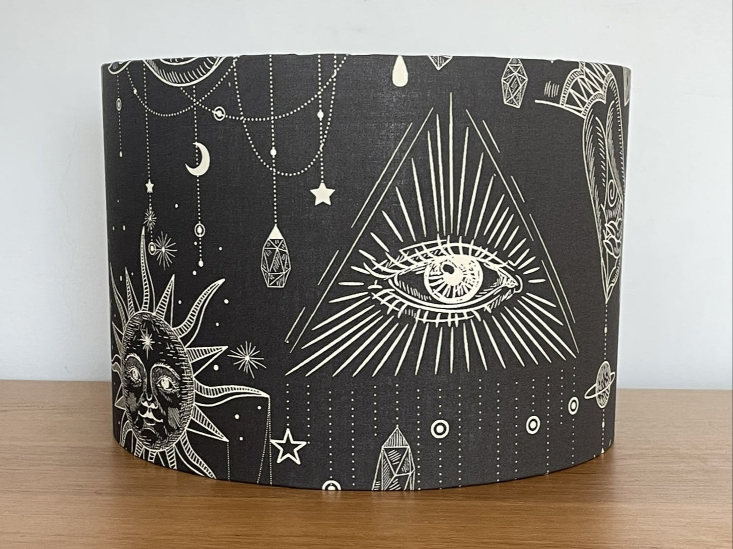 Black drum lampshade with white geometric and celestial designs on a dark grey background
