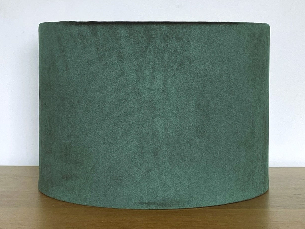 Green fabric lampshade on a wooden surface with a white background