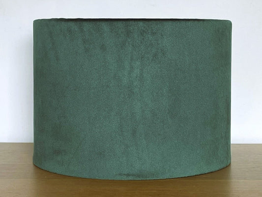 Green fabric lampshade on a wooden surface with a white background