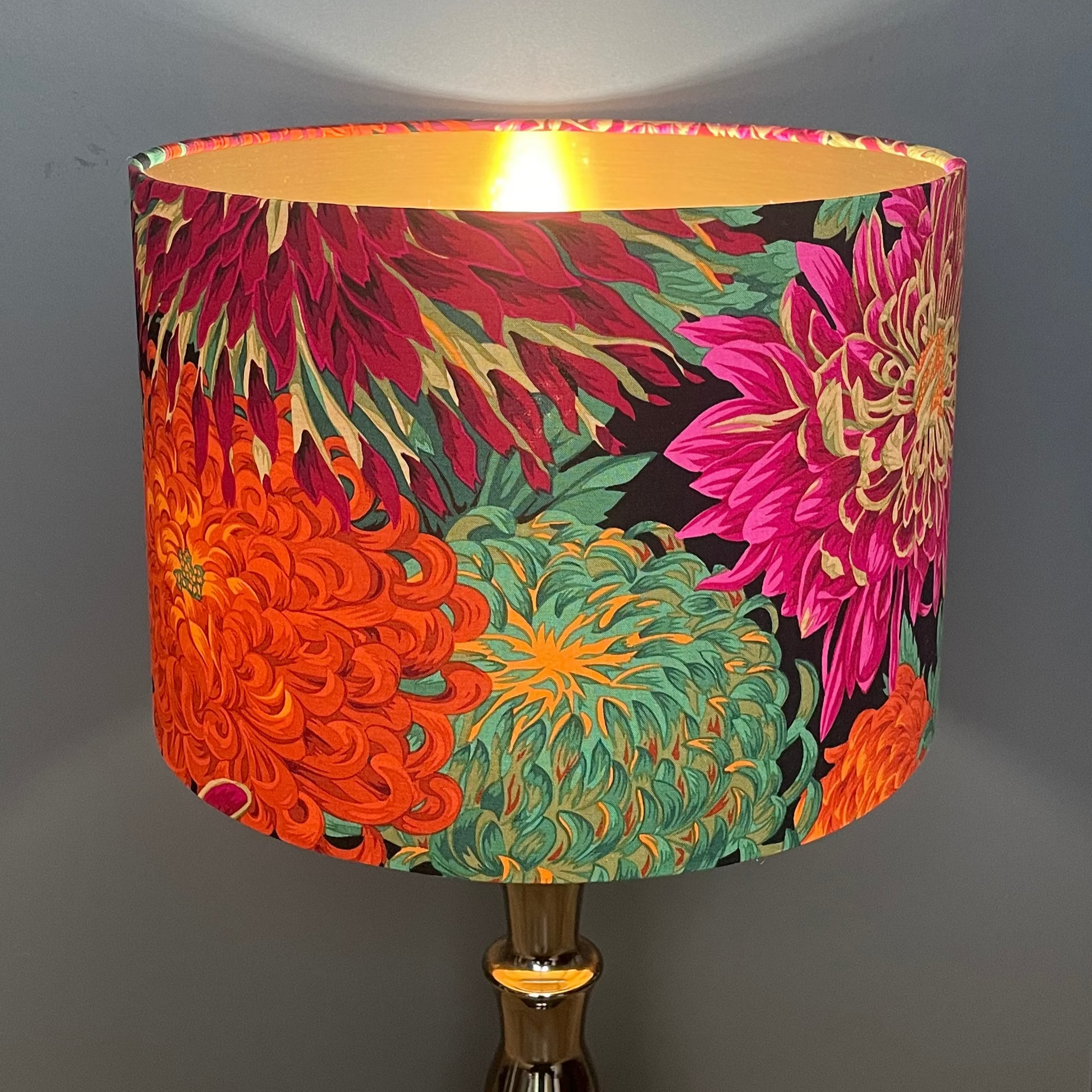 Colorful floral lampshade on a wooden table with a gray wall in the background