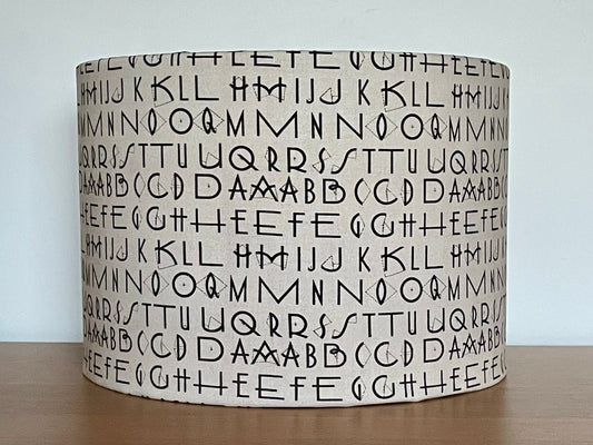 Tim Holtz Eclectic Elements charcoal fabric lampshade. Typography on a distressed cream background. With a choice of white or metallic lining.