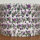 Floral patterned lampshade on a wooden surface with a white background