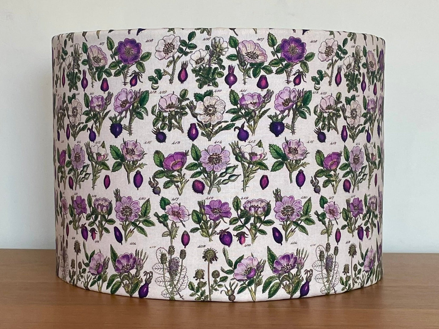 Floral patterned lampshade on a wooden surface with a white background