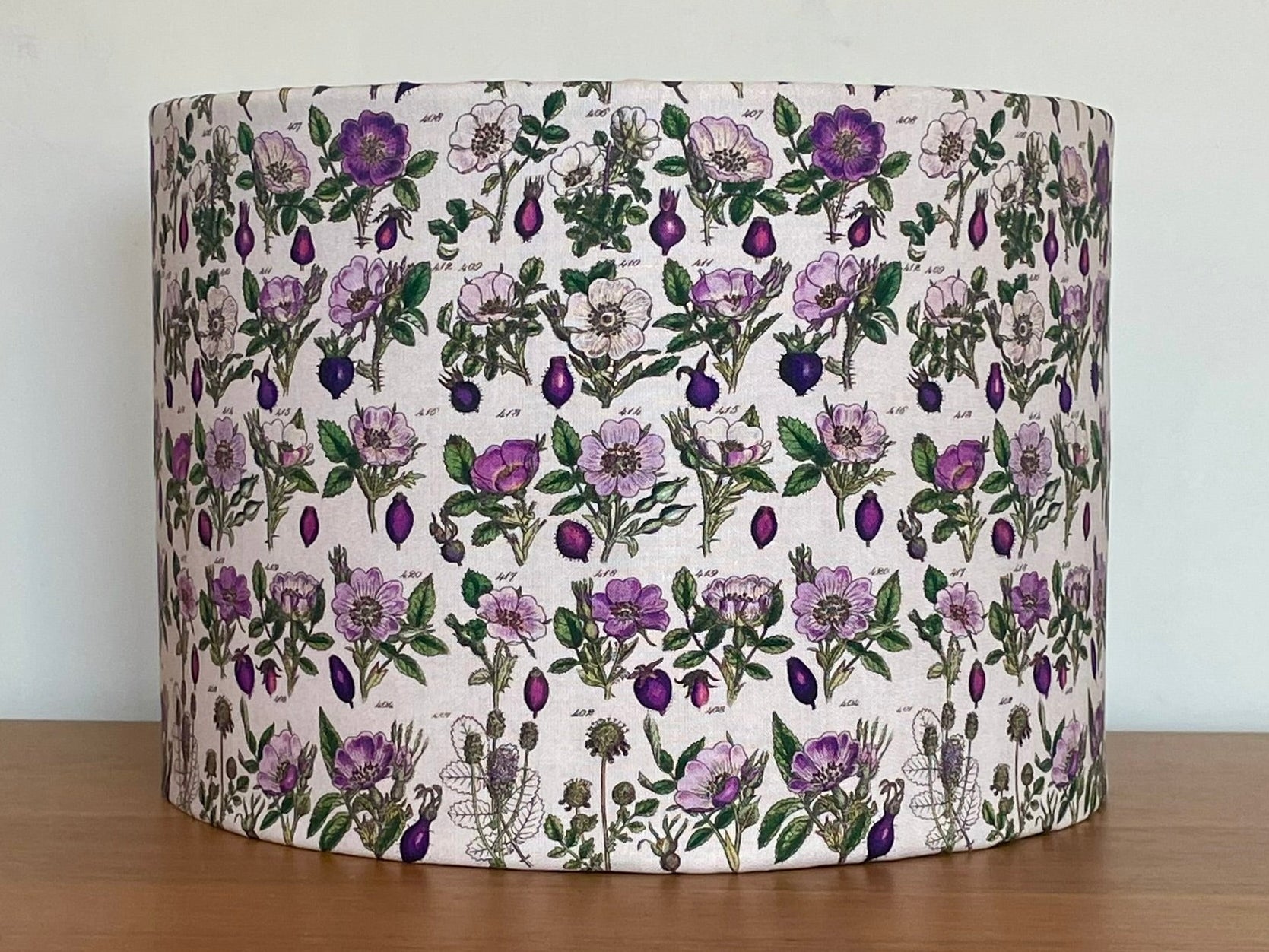 Floral patterned lampshade on a wooden surface with a white background