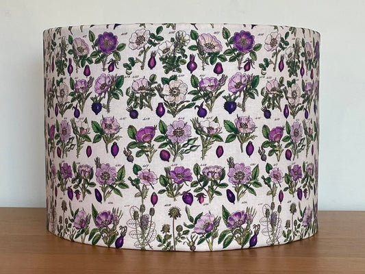 Floral patterned lampshade on a wooden surface with a white background