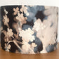 Floral-patterned lampshade on a wooden surface with a white background