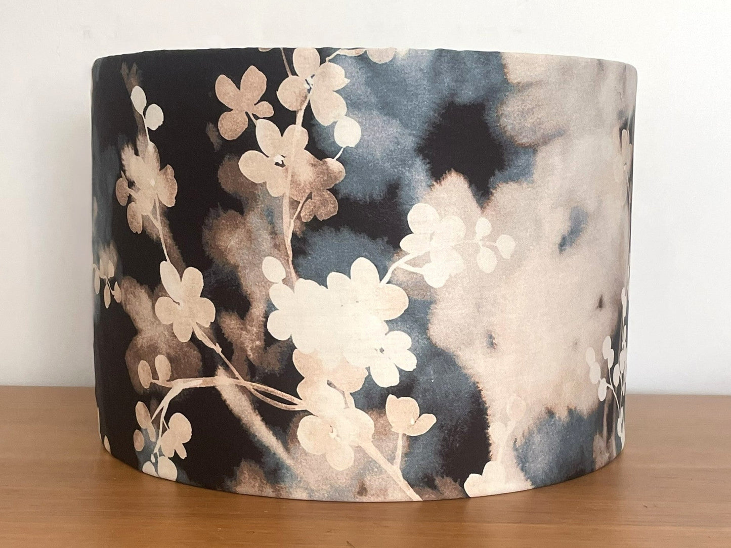 Floral-patterned lampshade on a wooden surface with a white background