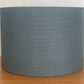 Blue striped fabric lampshade on a wooden surface with a white background