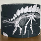 Lampshade with dinosaur skeleton design on a wooden surface