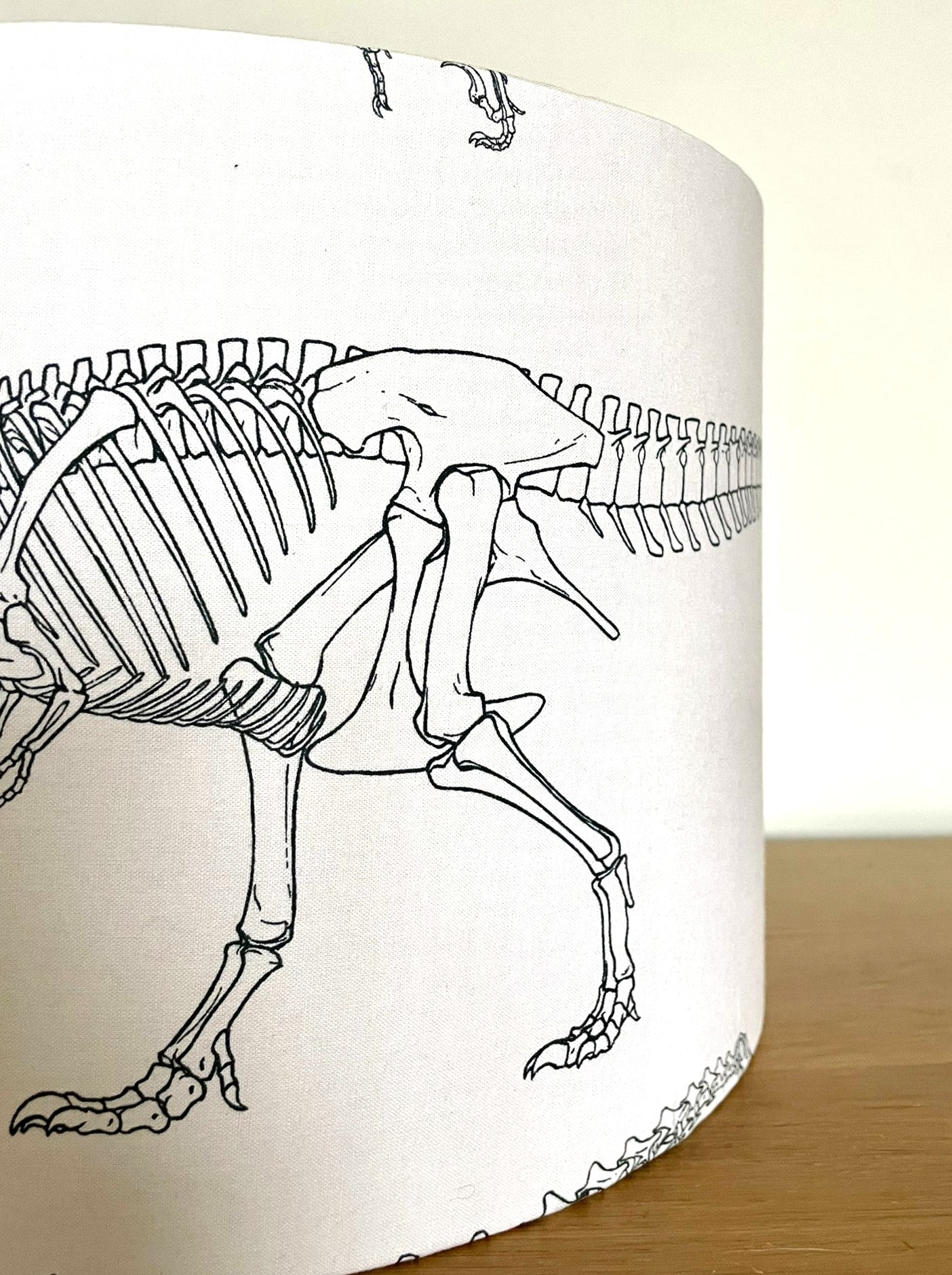 Lampshade with a black line drawing of a dinosaur skeleton on a white background